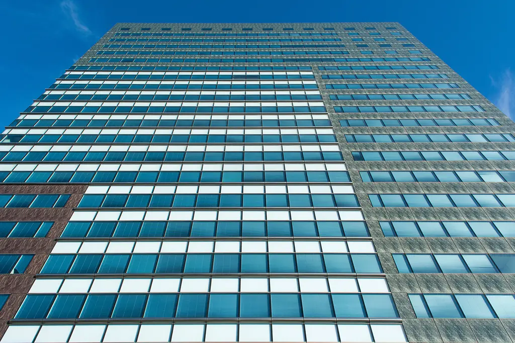 Kantoortoren met een glazen gevel tegen een blauwe lucht